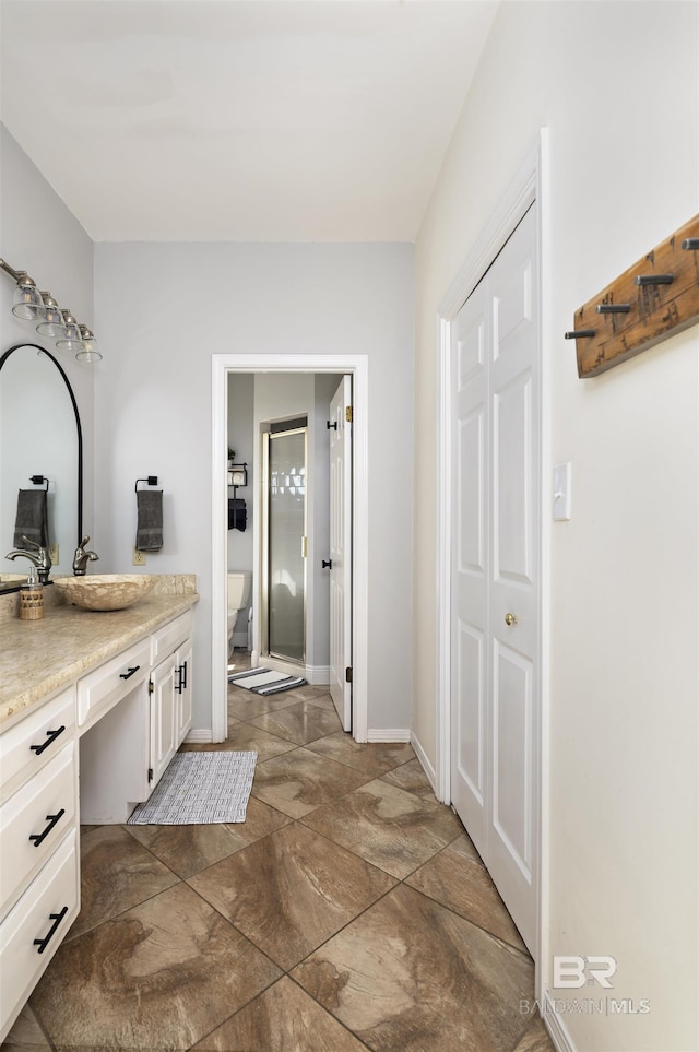 full bathroom with baseboards, a shower stall, and vanity
