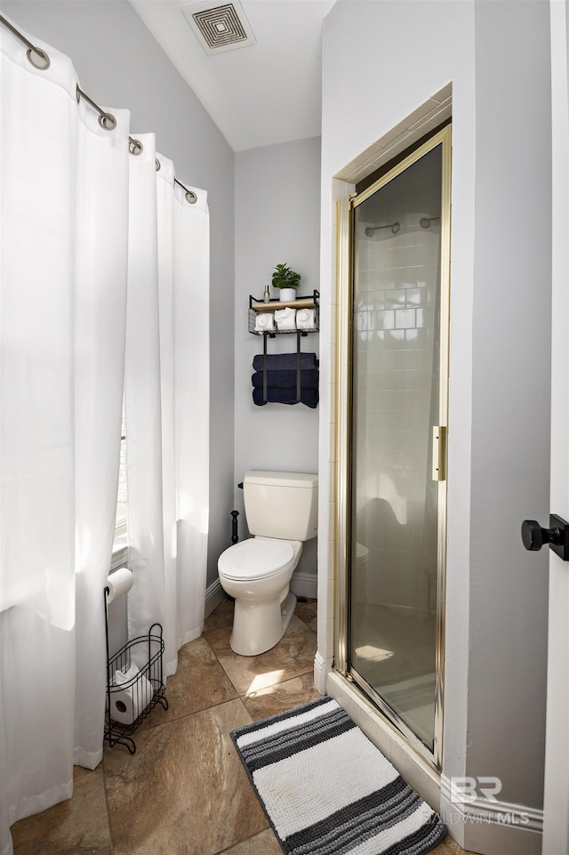 bathroom with visible vents, toilet, a stall shower, stone finish flooring, and baseboards