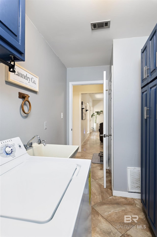 clothes washing area with washer / dryer, visible vents, cabinet space, and a sink