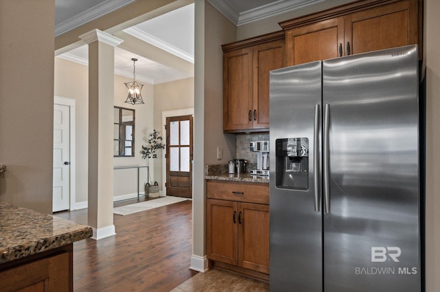 kitchen with stainless steel refrigerator with ice dispenser, ornate columns, dark hardwood / wood-style floors, dark stone counters, and decorative backsplash