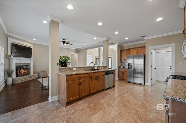 kitchen with ornamental molding, appliances with stainless steel finishes, sink, and a brick fireplace