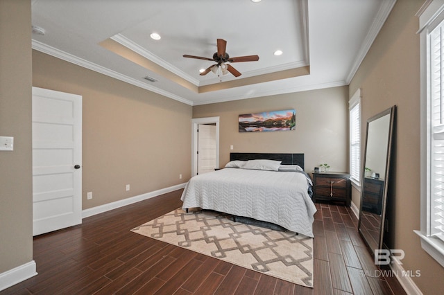 bedroom featuring dark wood-type flooring, ornamental molding, a raised ceiling, and ceiling fan