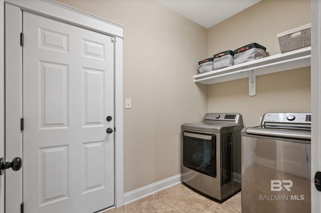 laundry area with light tile patterned floors and washer and clothes dryer