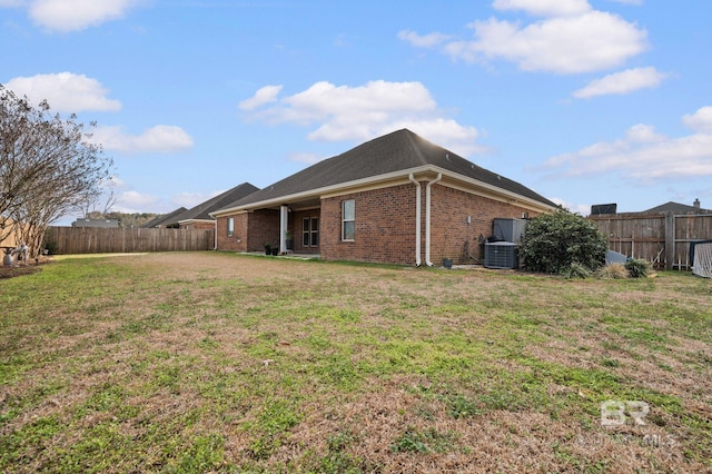 rear view of property with central AC unit and a lawn