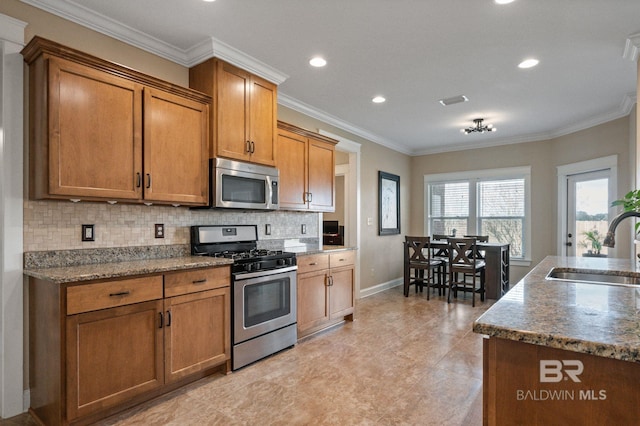 kitchen with sink, dark stone countertops, backsplash, stainless steel appliances, and ornamental molding