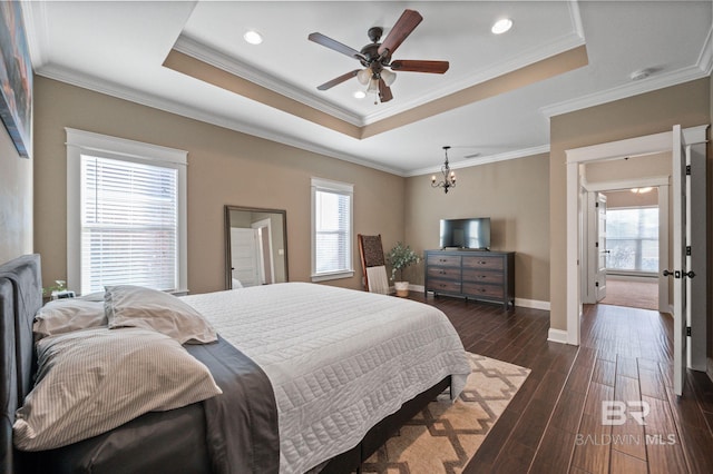 bedroom featuring multiple windows, dark hardwood / wood-style flooring, ornamental molding, and a raised ceiling