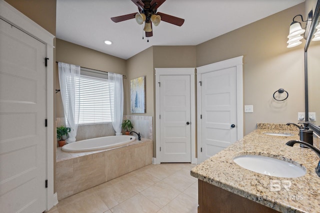 bathroom with tiled tub, vanity, tile patterned flooring, and ceiling fan