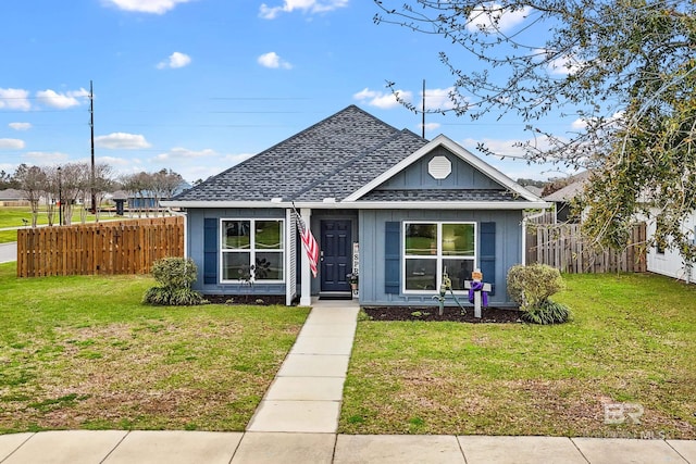 bungalow featuring a front lawn, fence, board and batten siding, and a shingled roof