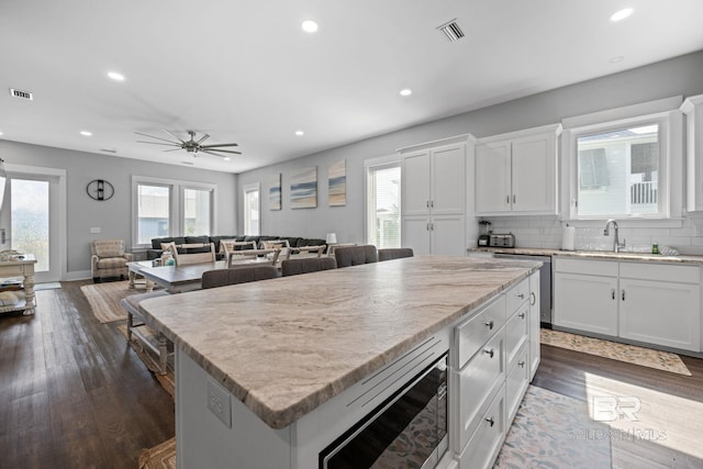 kitchen with appliances with stainless steel finishes, decorative backsplash, dark wood-type flooring, and ceiling fan