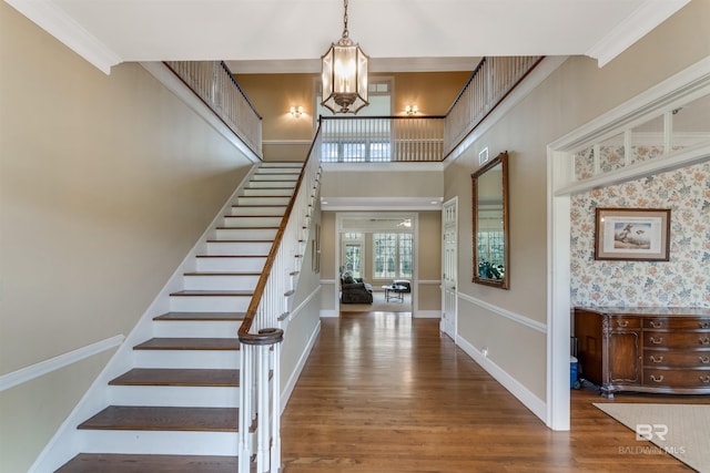 foyer featuring a high ceiling, baseboards, stairway, dark wood finished floors, and crown molding