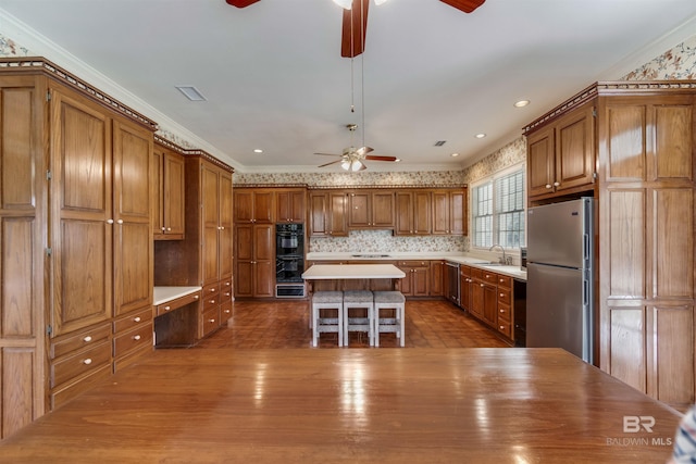 kitchen featuring brown cabinetry, a center island, light countertops, and black appliances