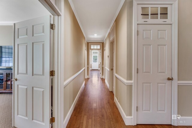hall with crown molding, baseboards, and wood finished floors