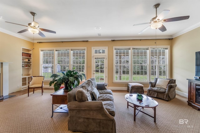 living room featuring ceiling fan, ornamental molding, a fireplace, and a wealth of natural light