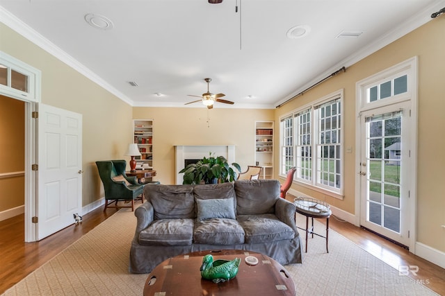 living room with baseboards, visible vents, ceiling fan, ornamental molding, and wood finished floors