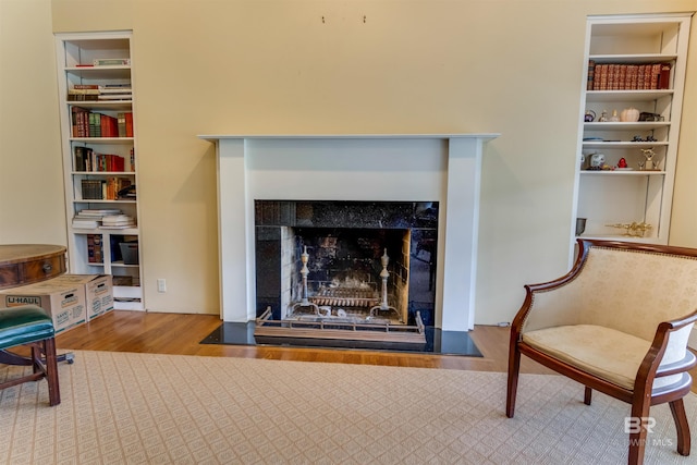 sitting room with a fireplace with flush hearth, light wood-type flooring, and built in features