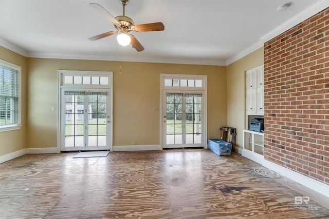 interior space with brick wall, plenty of natural light, baseboards, and crown molding