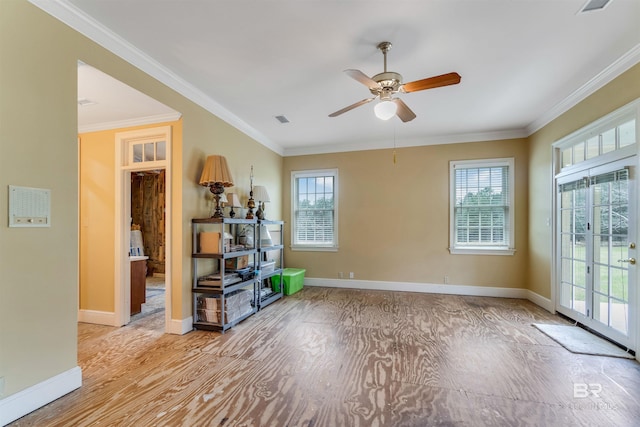 spare room featuring a healthy amount of sunlight, visible vents, baseboards, and crown molding