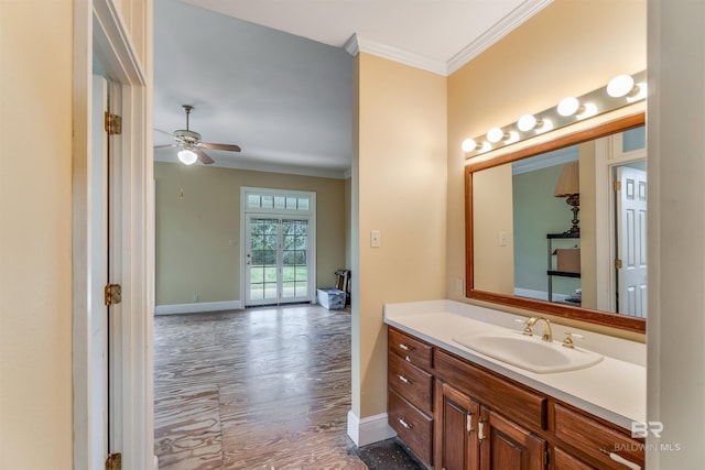 bathroom featuring baseboards, ceiling fan, ornamental molding, wood finished floors, and vanity