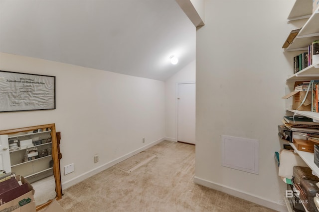 interior space with vaulted ceiling, light carpet, and baseboards