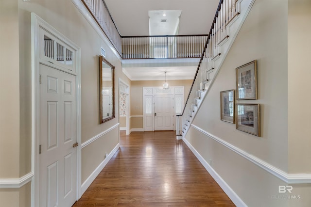 foyer with wood finished floors, visible vents, a towering ceiling, baseboards, and stairway