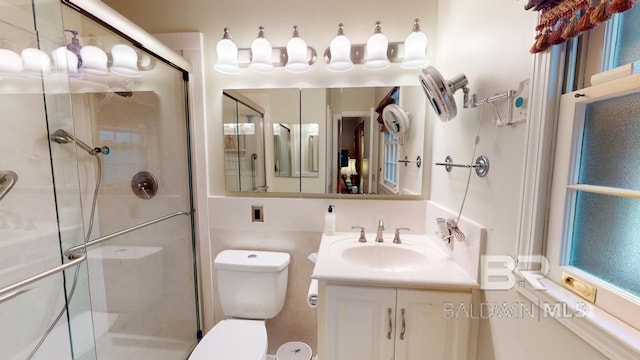 bathroom featuring a shower with door, vanity, and toilet