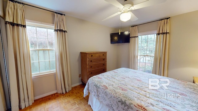 bedroom with light parquet flooring, multiple windows, and ceiling fan