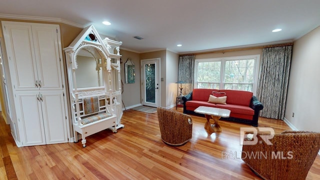 living room featuring crown molding and light hardwood / wood-style flooring