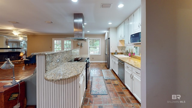 kitchen featuring sink, light stone countertops, appliances with stainless steel finishes, white cabinetry, and island exhaust hood