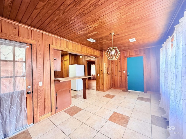 613 S Carney St, Atmore, AL 36502 - kitchen with freestanding refrigerator, wooden walls, wood ceiling, light tile patterned floors, and pendant lighting