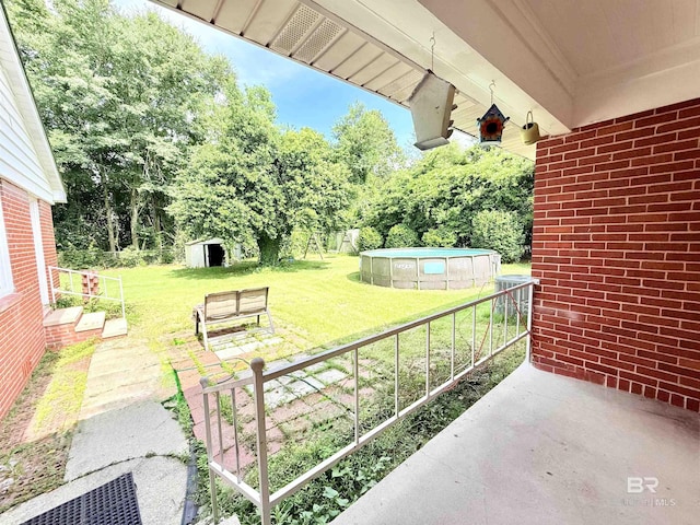 613 S Carney St, Atmore, AL 36502 - view of patio featuring a storage unit, an outdoor pool, and view of wooded area