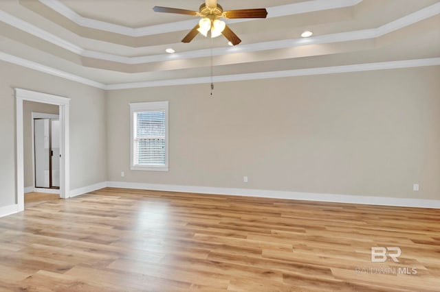 spare room featuring light hardwood / wood-style flooring, ornamental molding, a raised ceiling, and ceiling fan