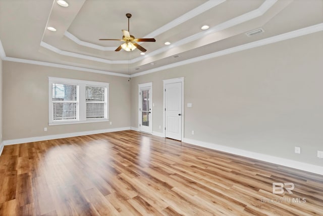 empty room with ornamental molding, a raised ceiling, ceiling fan, and light wood-type flooring