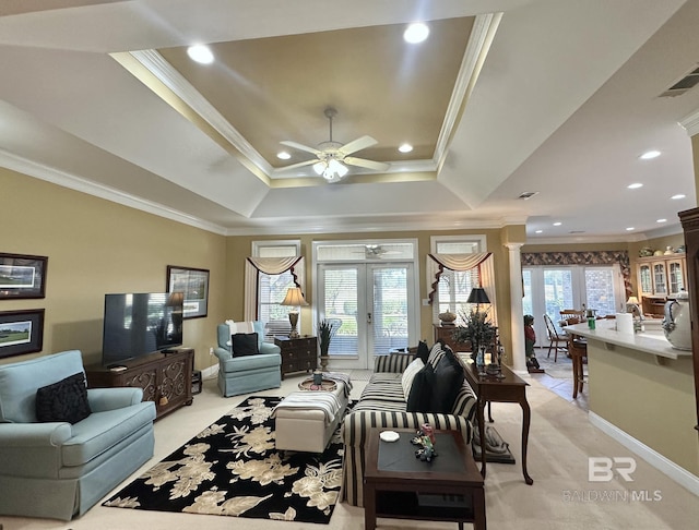 living room with ceiling fan, a raised ceiling, ornamental molding, and french doors