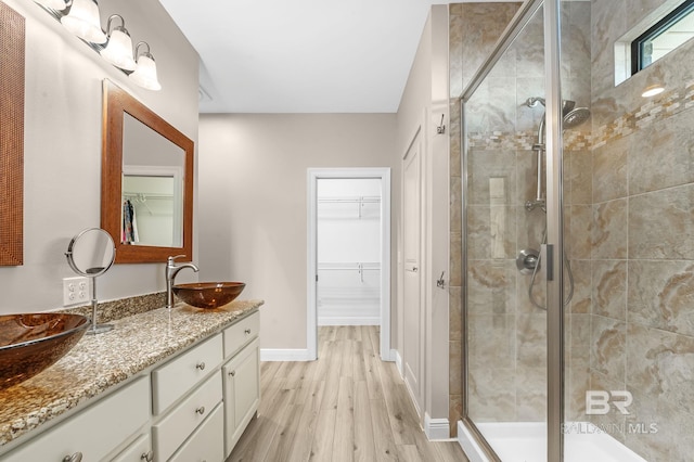 26635 Terry Cove Dr, Orange Beach, AL 36561 - full bathroom with wood finished floors, vanity, baseboards, a stall shower, and a walk in closet