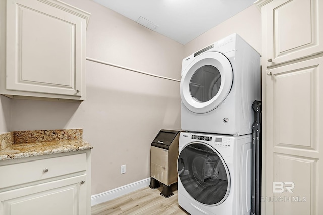 26635 Terry Cove Dr, Orange Beach, AL 36561 - laundry area featuring visible vents, baseboards, stacked washing maching and dryer, cabinet space, and light wood finished floors