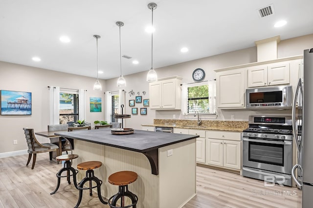 26635 Terry Cove Dr, Orange Beach, AL 36561 - kitchen with visible vents, a kitchen island, decorative light fixtures, stainless steel appliances, and a sink