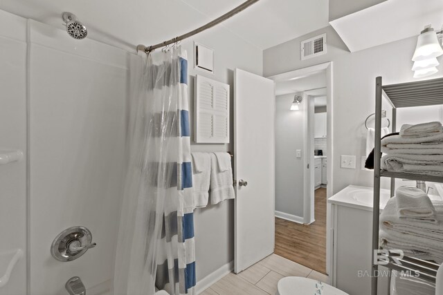 full bath featuring vanity, visible vents, shower / tub combo with curtain, and wood finish floors