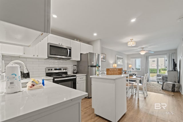 kitchen with light wood finished floors, appliances with stainless steel finishes, a kitchen island, and light countertops