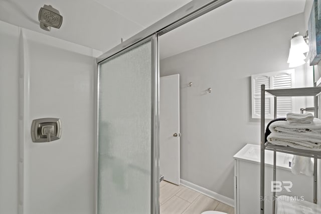 full bath featuring baseboards, wood finished floors, and a shower stall