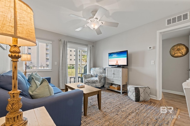 living area featuring visible vents, ceiling fan, baseboards, and wood finished floors