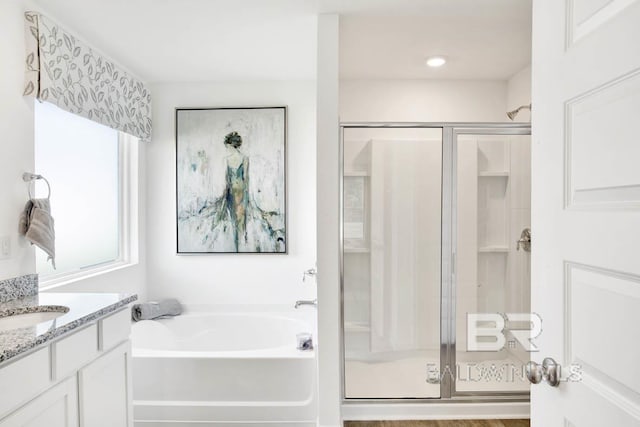 bathroom featuring a stall shower, a garden tub, and vanity