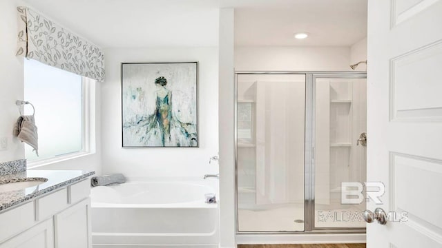 full bathroom with a stall shower, a bath, and vanity