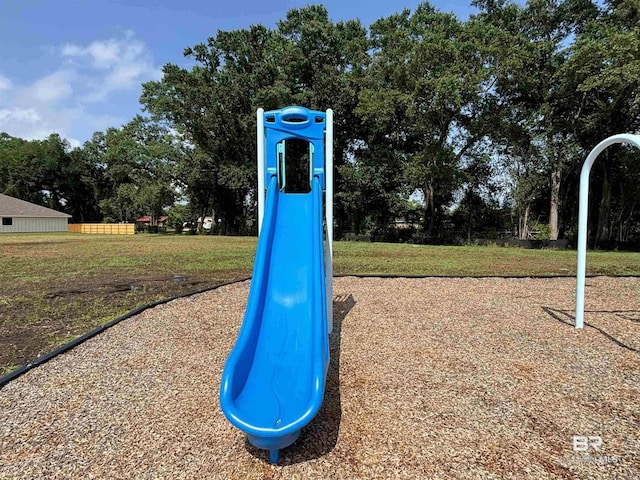 community play area featuring view of wooded area and a lawn