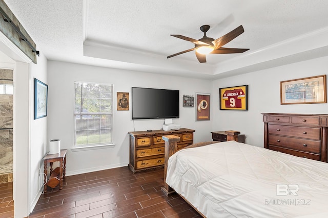 bedroom with a raised ceiling, a textured ceiling, dark wood-type flooring, and ceiling fan