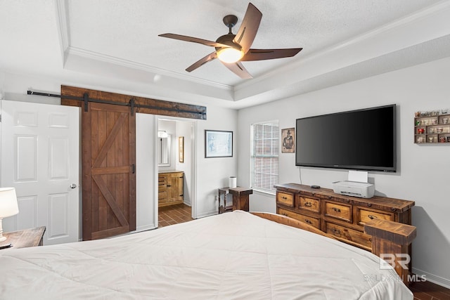 bedroom featuring a textured ceiling, crown molding, ensuite bath, a barn door, and ceiling fan