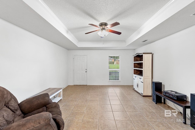 living room featuring a tray ceiling, ceiling fan, light tile patterned floors, and a textured ceiling