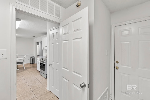 hall featuring a textured ceiling and light tile patterned flooring