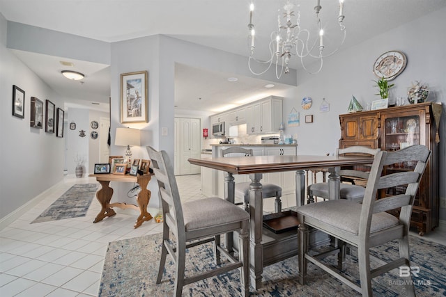 dining area with light tile patterned floors, baseboards, and an inviting chandelier