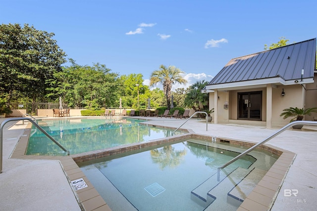 pool with a patio, fence, and a hot tub