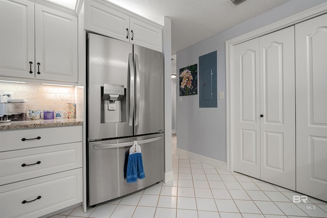kitchen with tasteful backsplash, baseboards, stainless steel fridge, electric panel, and a textured ceiling